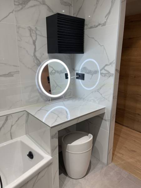 Confection d'une coiffeuse sur mesure carrelée effet marbre blanc avec un miroir rond led de taille proportionnée 
