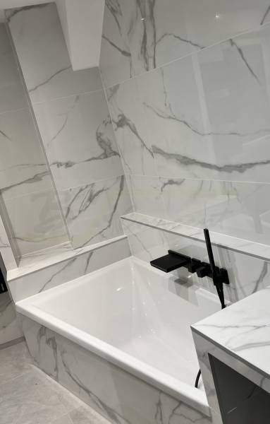Baignoire asymétrique effet marbre blanc avec une robinetterie noire moderne
