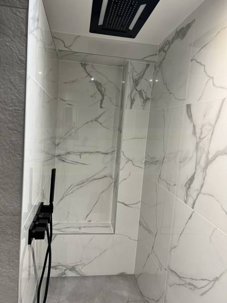 Création d'une douche à l'italienne cosy et cachée avec banc carrelé effet marbre blanc et tête de douche proposant de la musique et des lumières à proximité de Strasbourg